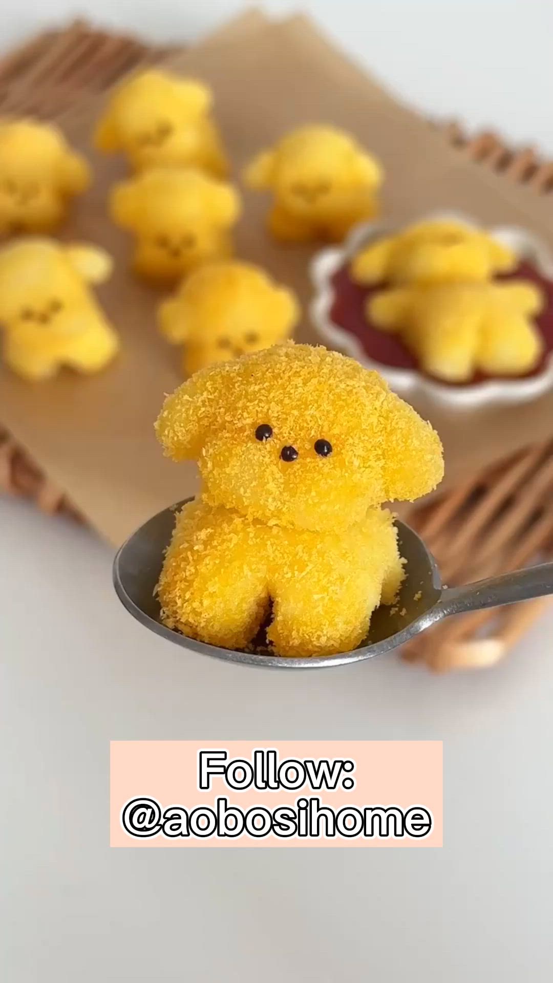 This may contain: a small yellow teddy bear sitting on top of a spoon next to some little cookies