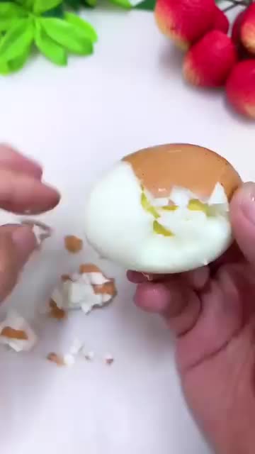 This may contain: a person is peeling an egg into a bowl