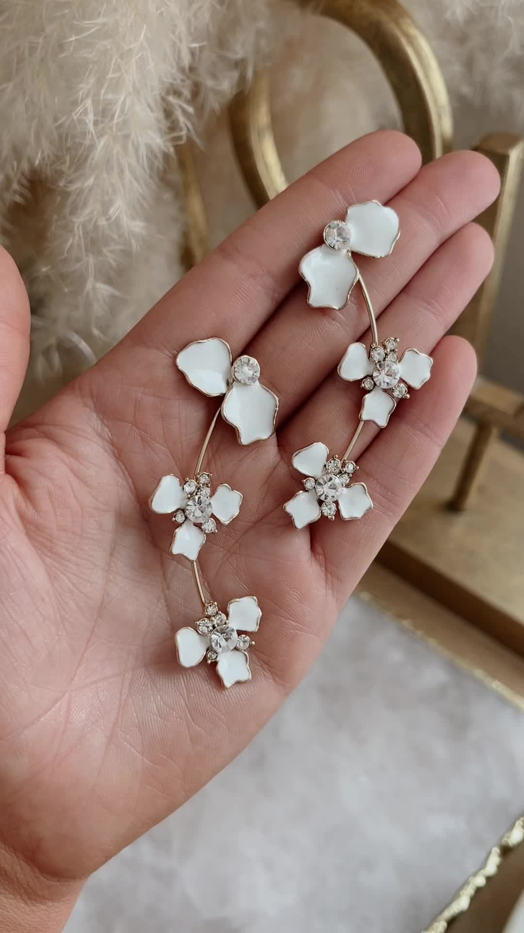 This may contain: the white flower earrings are being held in someone's hand, while they have been placed