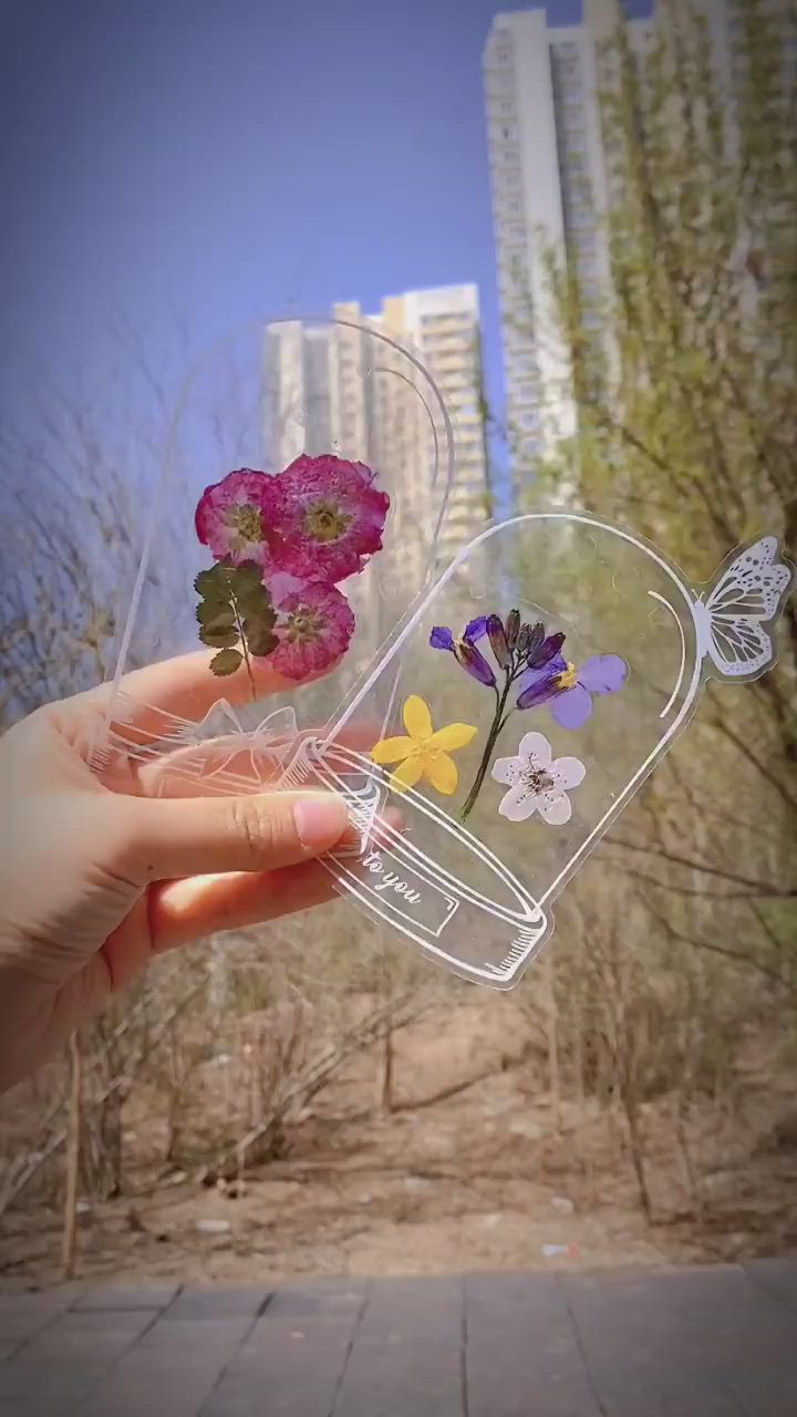 This may contain: a person holding flowers in their hand with buildings in the backgroung behind them