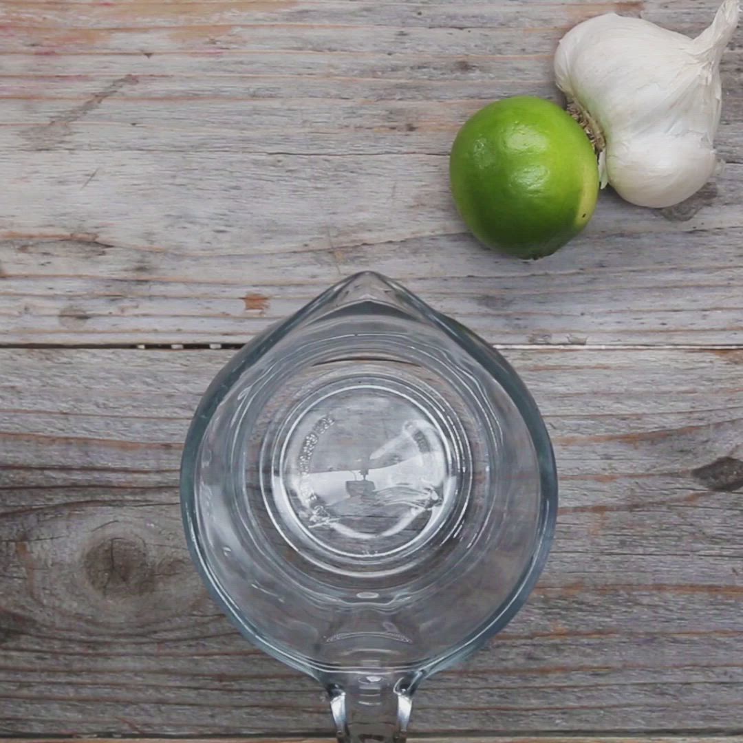 This may contain: an onion and lime on a wooden table next to a glass bowl with water in it