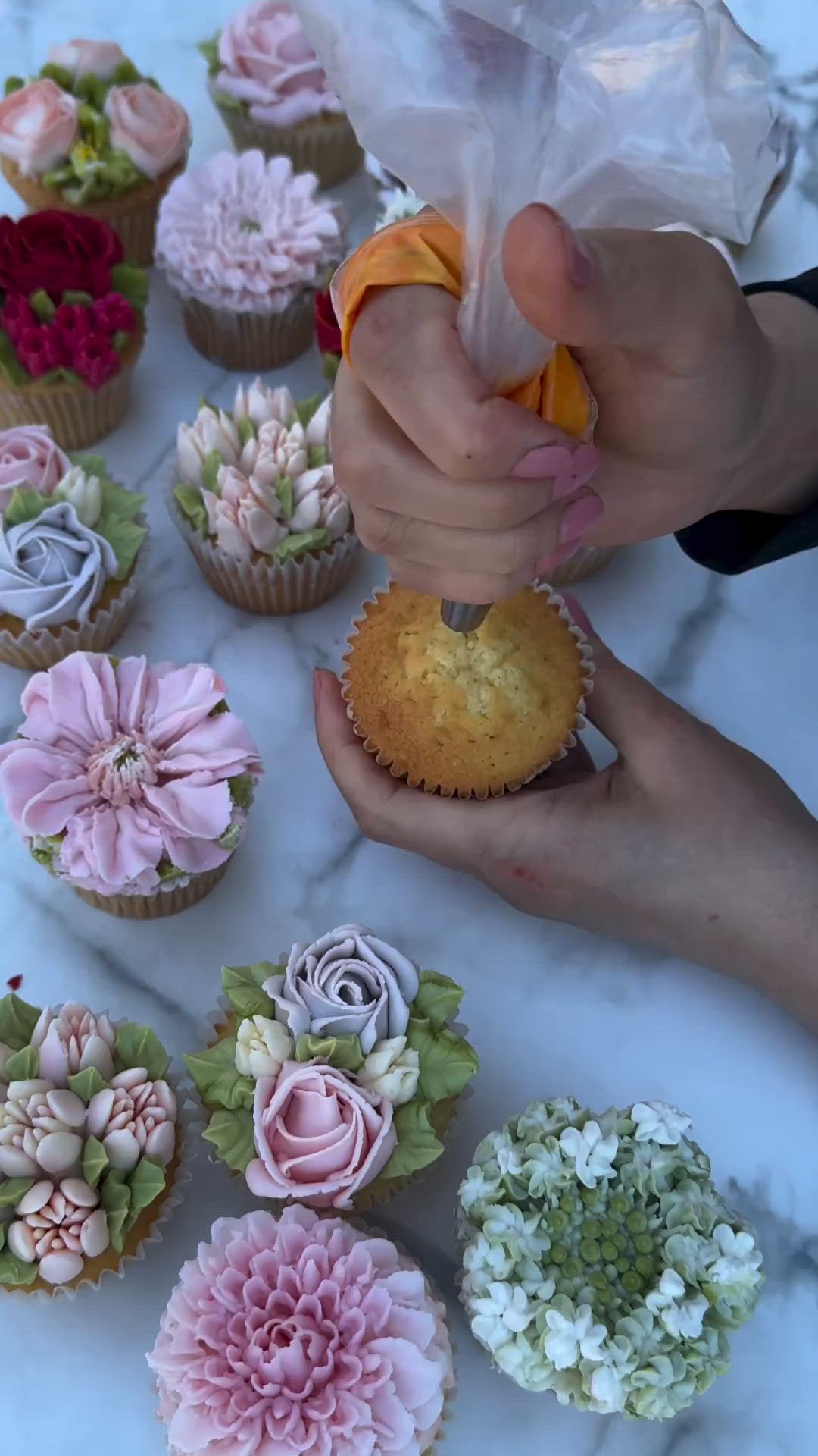 This may contain: someone is decorating cupcakes with flowers and icing