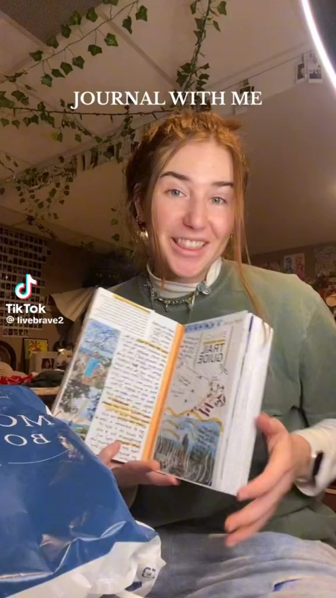 This may contain: a woman is holding an open book in front of her face and smiling at the camera