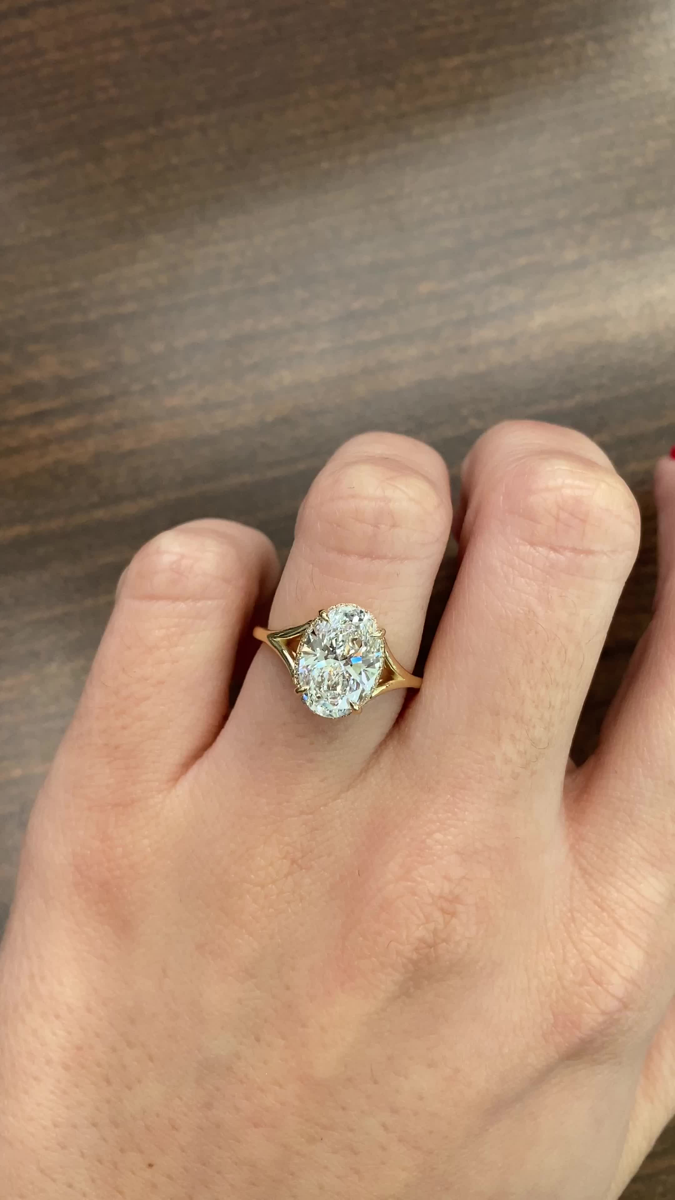 This may contain: a person's hand holding a ring with a diamond in it on top of a wooden table