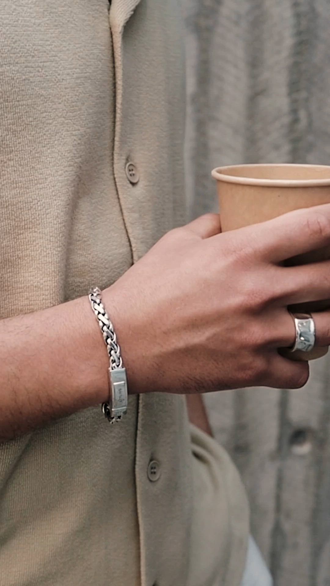 This contains: Man wearing silver bracelets, necklaces and rings.