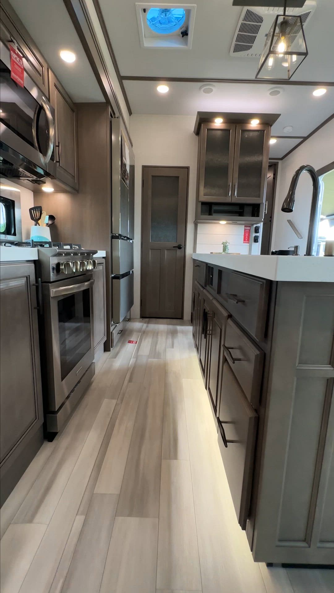 This may contain: a galley kitchen with stainless steel appliances and wood flooring is shown in this image