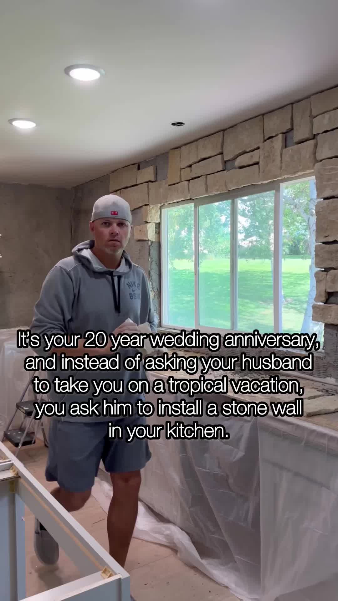 This may contain: a man standing next to a window in a house under construction with the words, it's your 20 year wedding anniversary and instead of asking you husband to take you on a tropical vacation