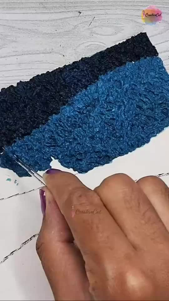 This may contain: someone is using scissors to cut the blue and black material on top of each other