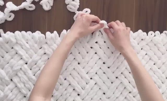 This may contain: someone is making a woven wall hanging with white yarn and crochet hooks on it