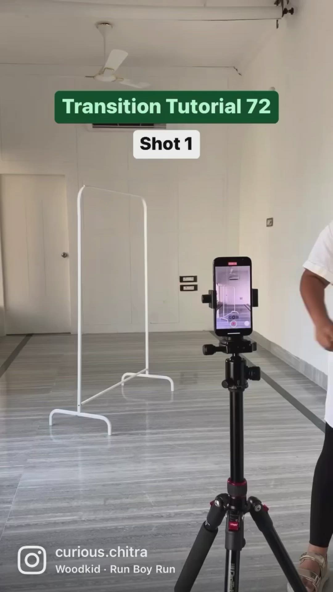 This may contain: a man taking a photo with his cell phone on a tripod in an empty room