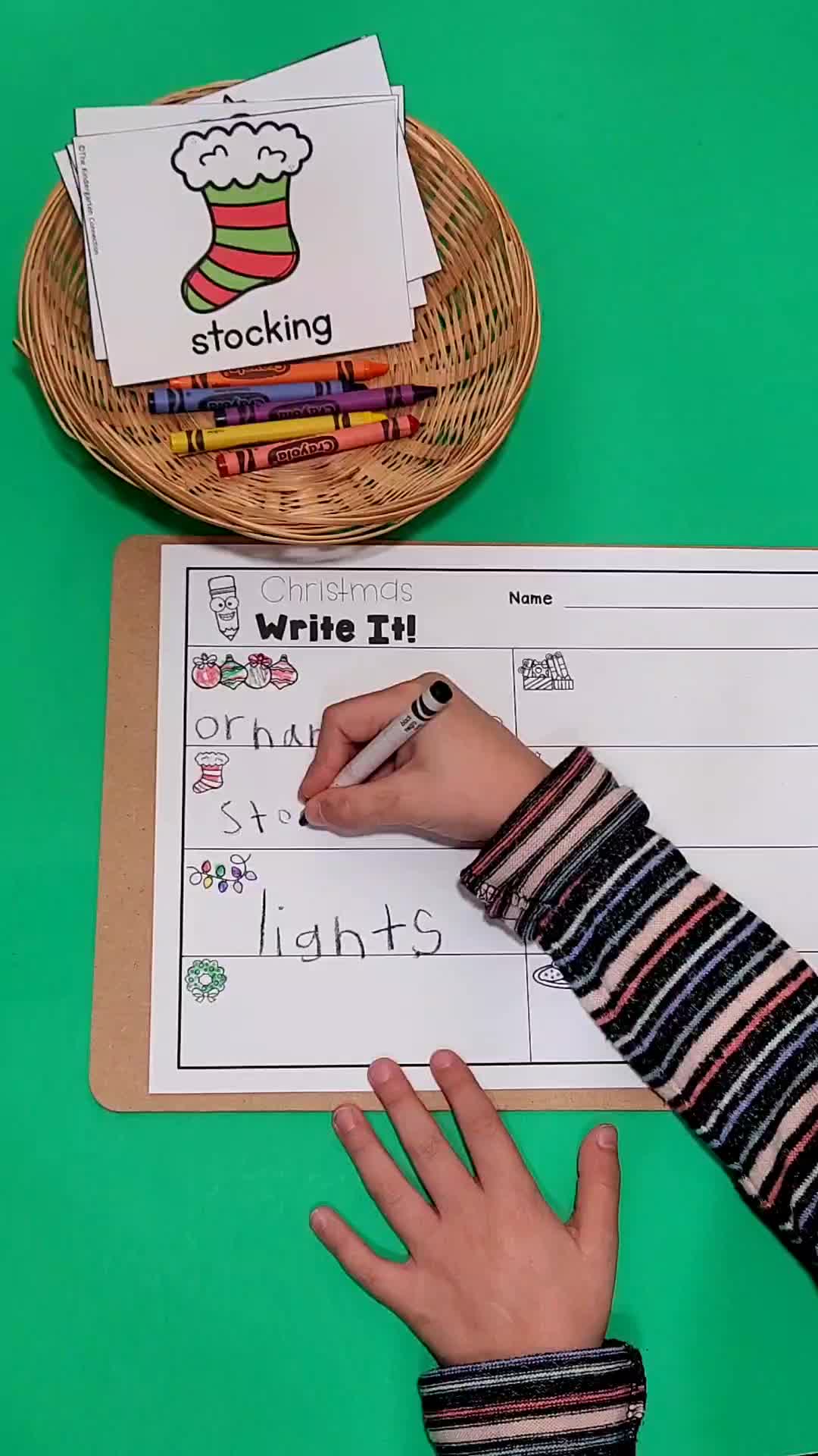 This may contain: a person writing on a piece of paper next to a basket of crayons