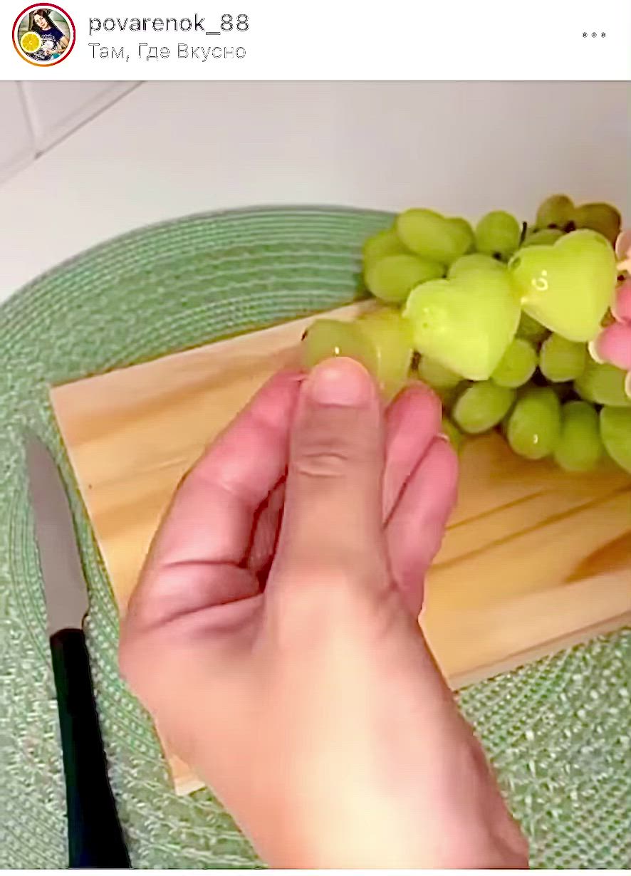 This may contain: a person is holding two glasses with fruit in them and one glass has grapes on it