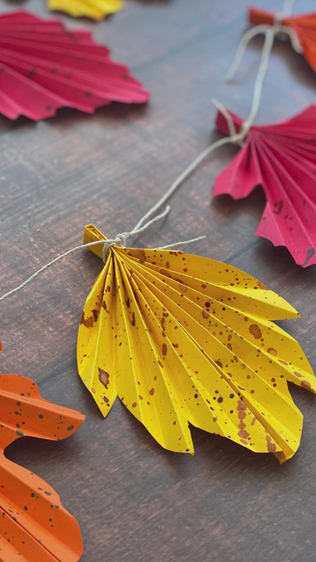 This may contain: colorful paper leaves are laid out on a table with twine strings attached to them