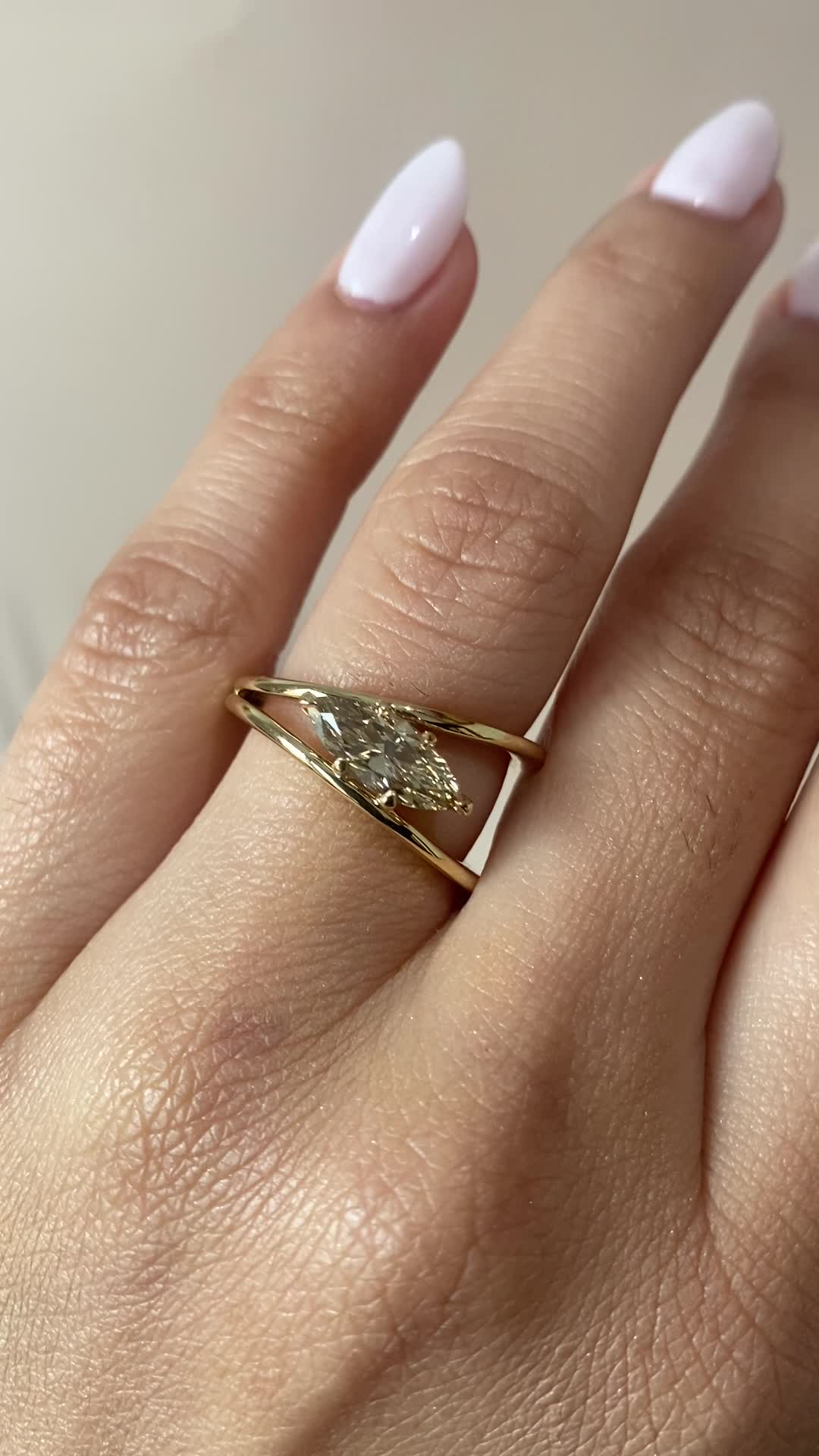 This may contain: a woman's hand wearing a gold ring with a diamond in the middle and a leaf on it