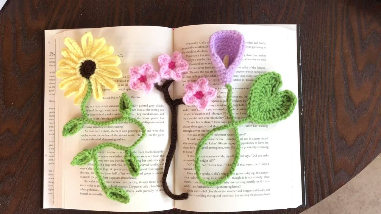 This may contain: an open book with crocheted flowers on it sitting on top of a table