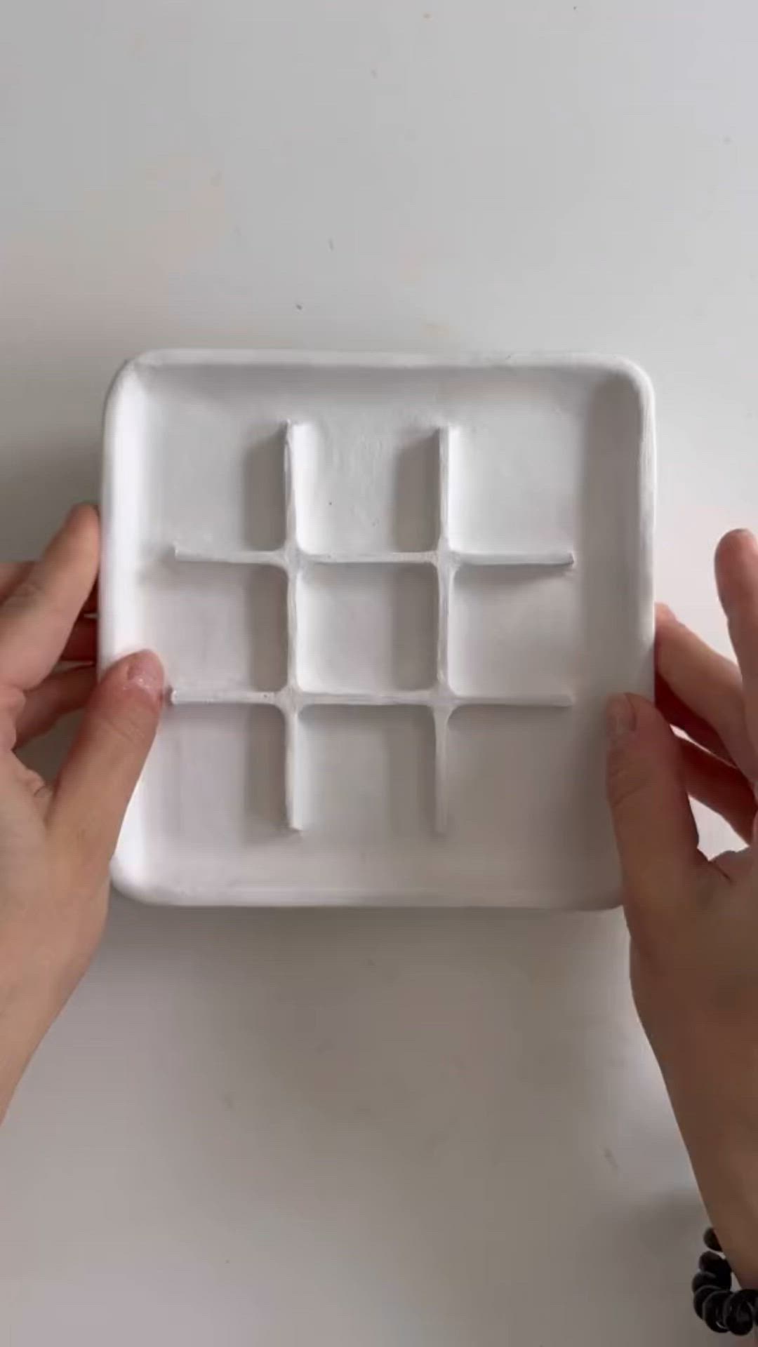 This may contain: a person holding up a small waffle cake pan