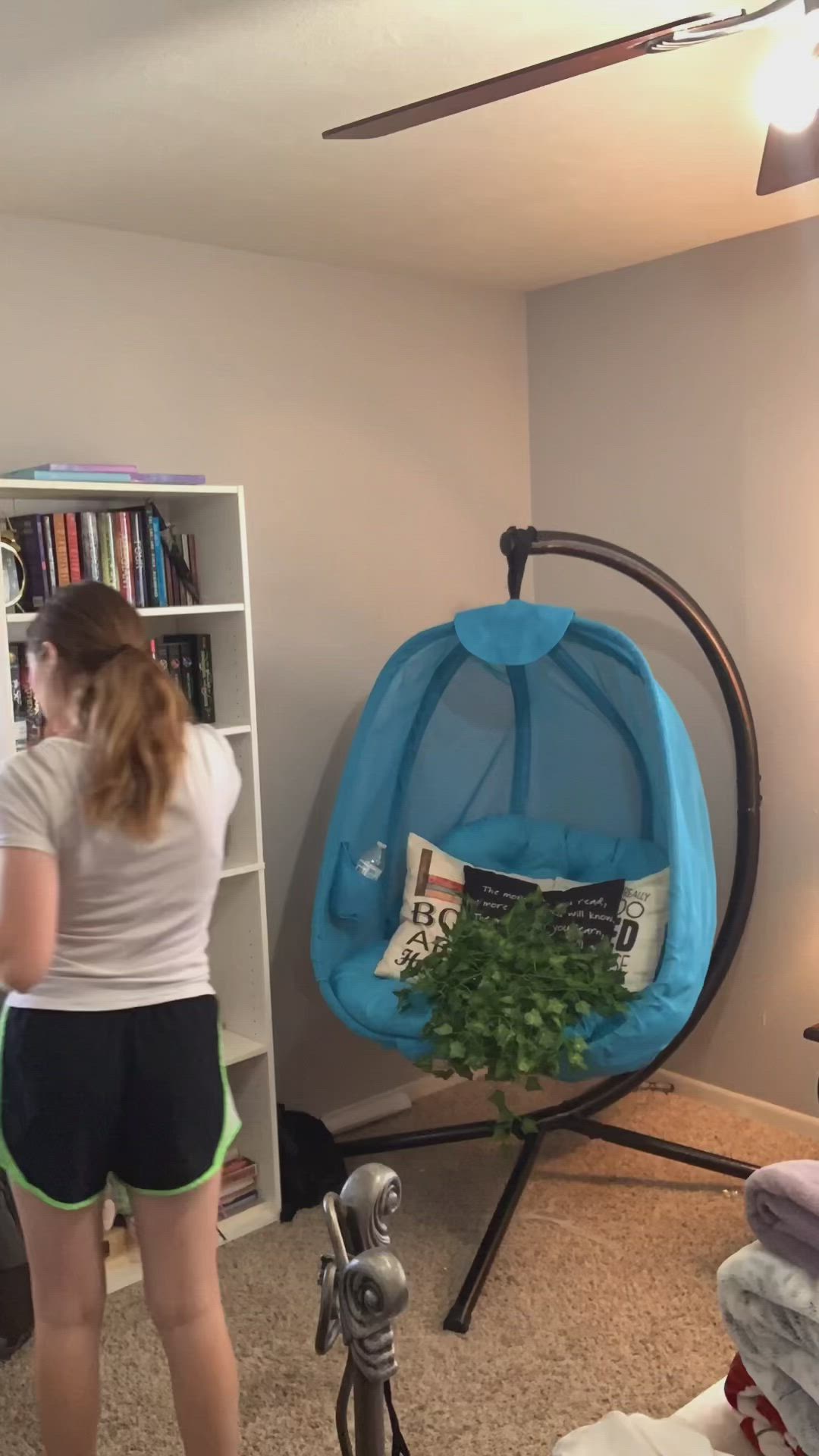 This may contain: a woman is hanging plants from the ceiling