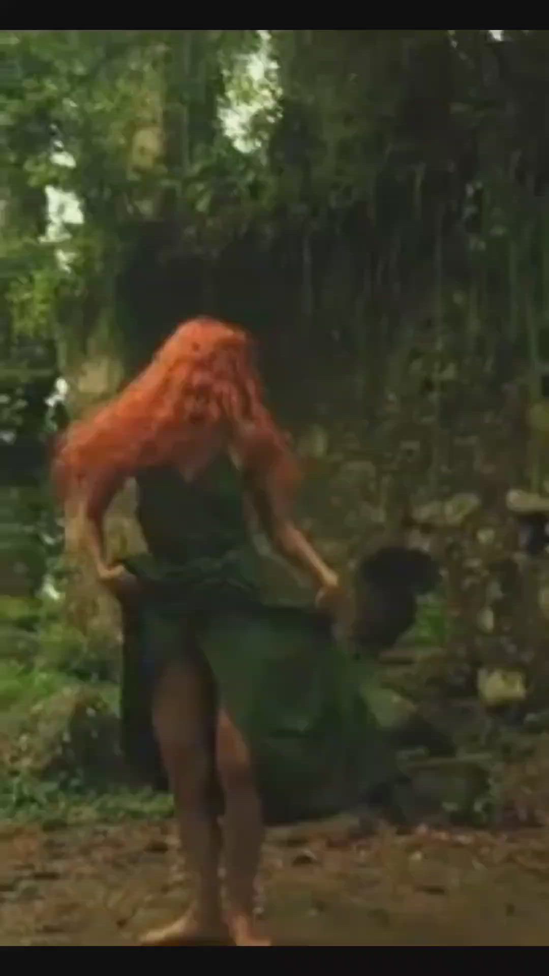 This may contain: a woman with red hair is walking through the woods