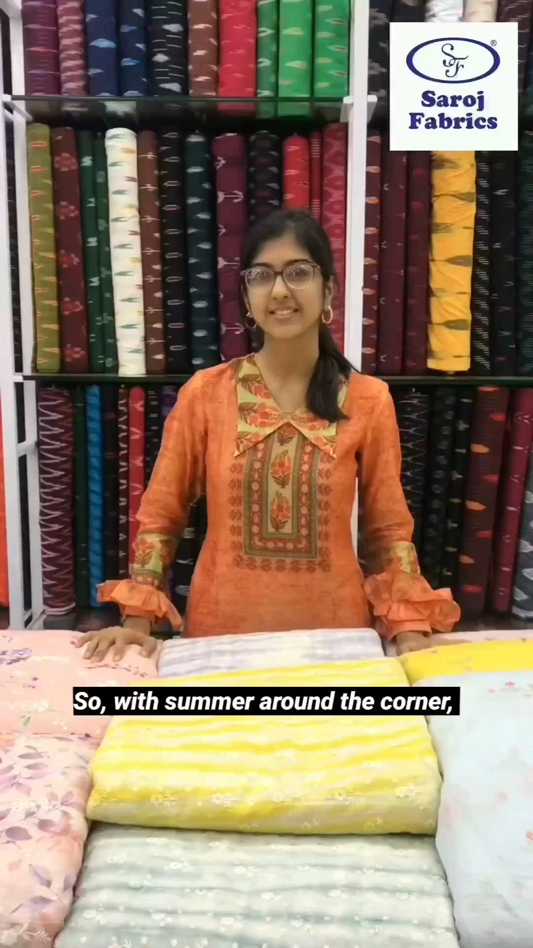 This may contain: a woman standing in front of a display of fabrics