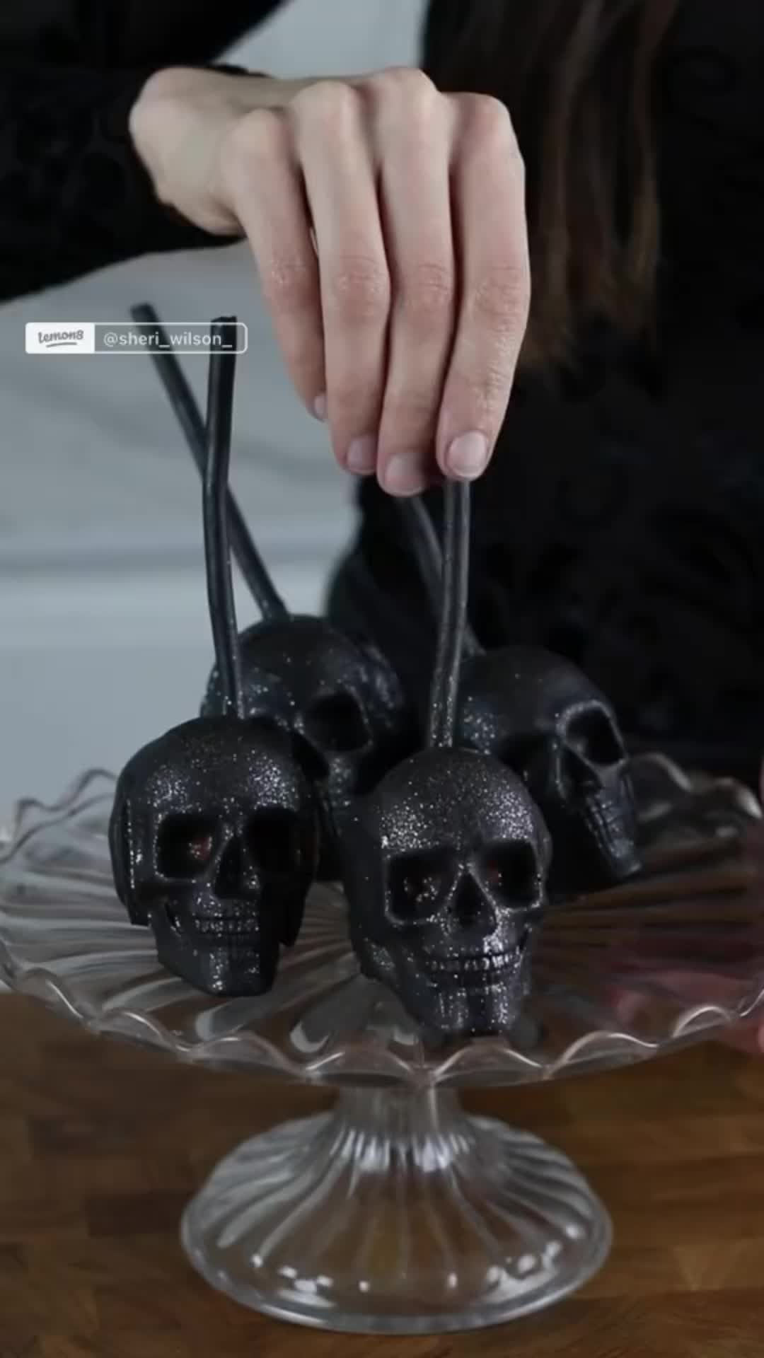 This may contain: a person holding two black skulls on top of a glass plate