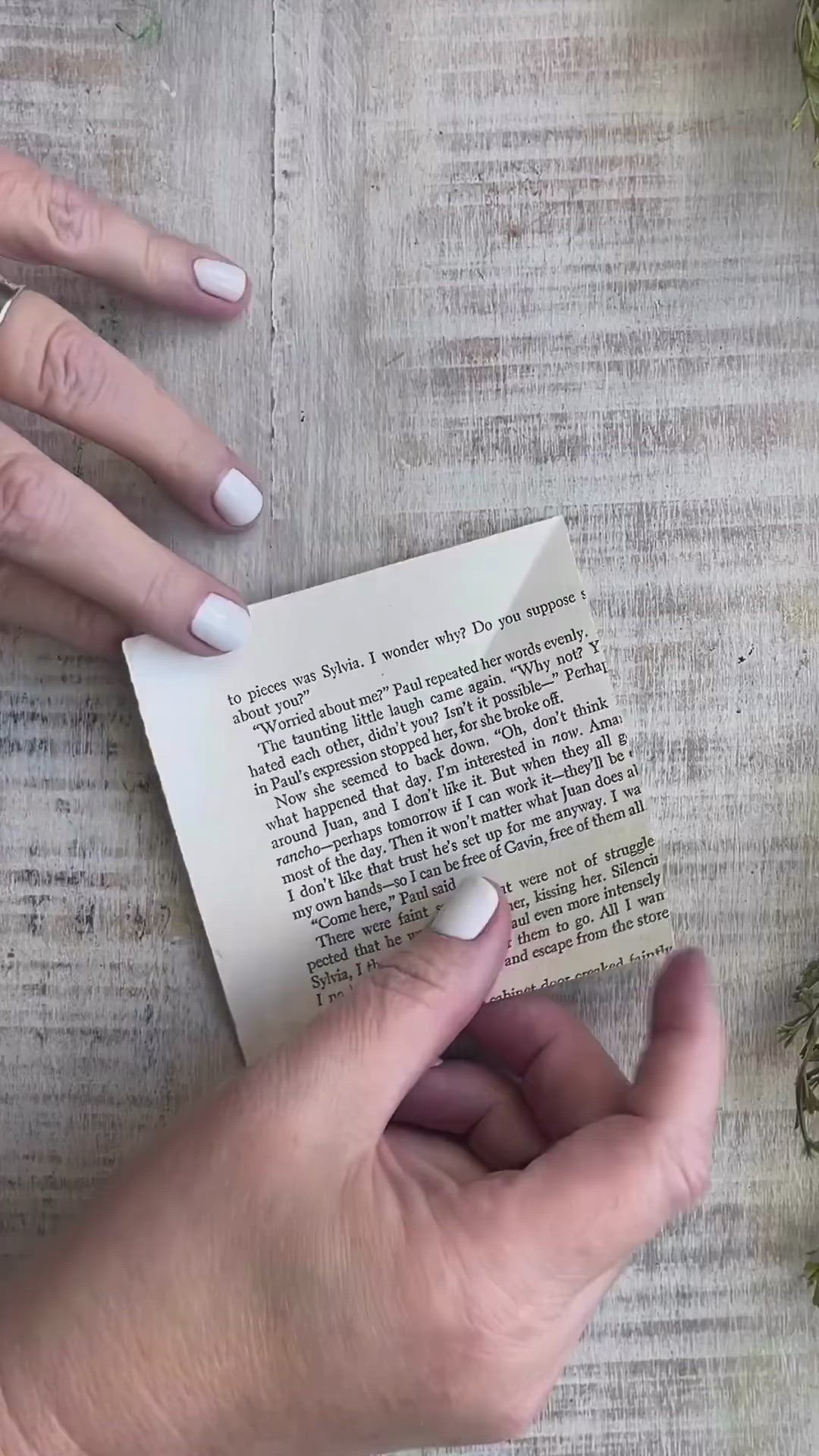 This may contain: a woman's hand with white nails and manicures is holding an origami bird