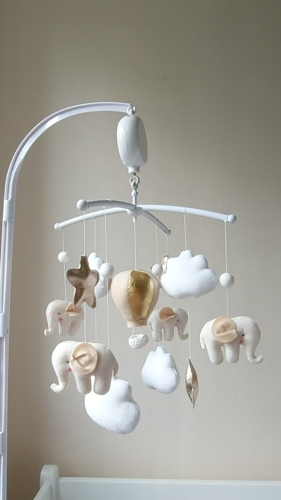 This may contain: a baby crib with an animal mobile hanging from it's side