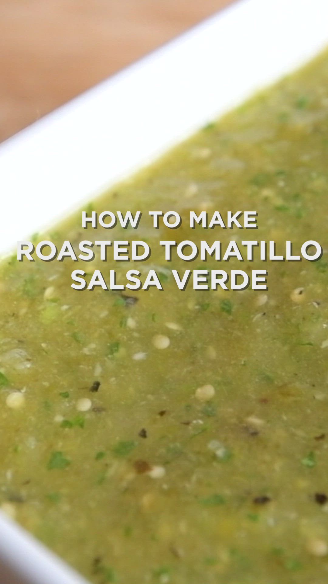 This may contain: how to make roasted tomato salsa verde in a white bowl on a wooden table