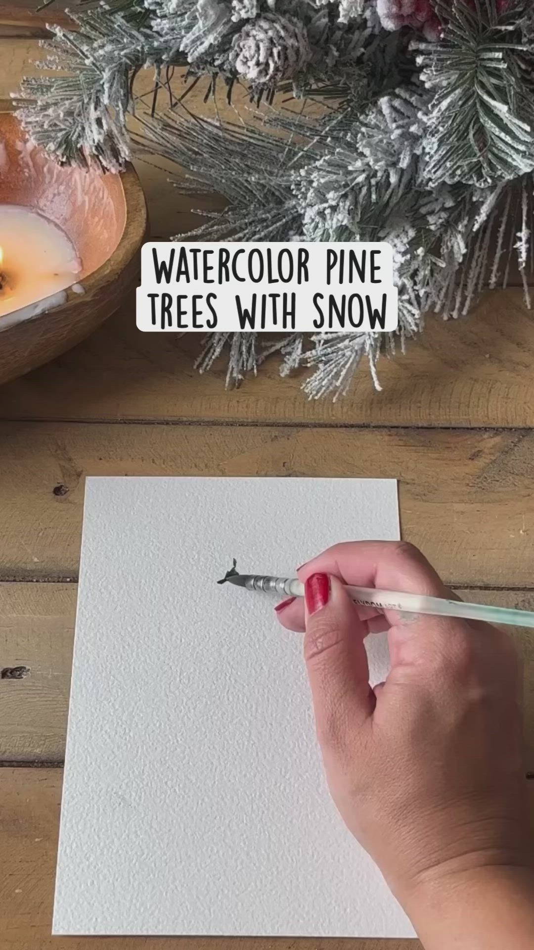 This may contain: someone is holding a pen and writing on paper with watercolor pine trees in the background