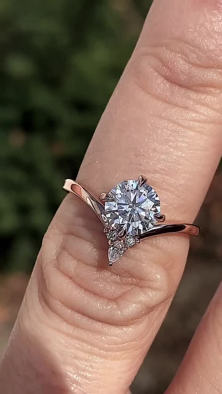 This may contain: a woman's hand with a diamond ring on top of her finger, showing the center stone