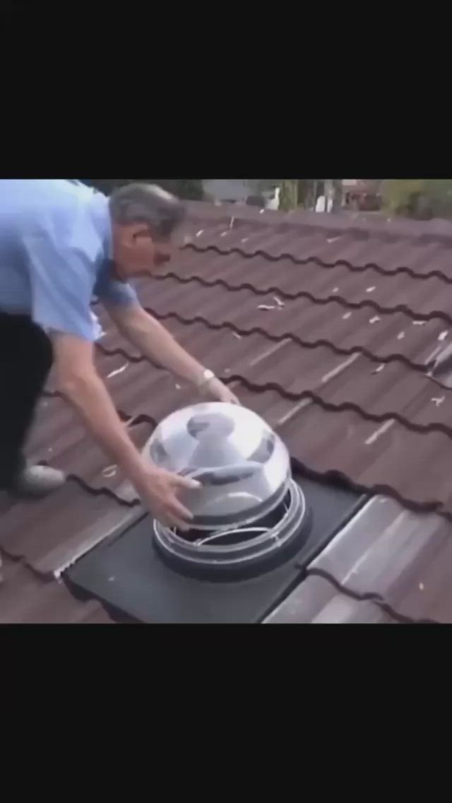 This may contain: a man is bending over to inspect the roof ventilator