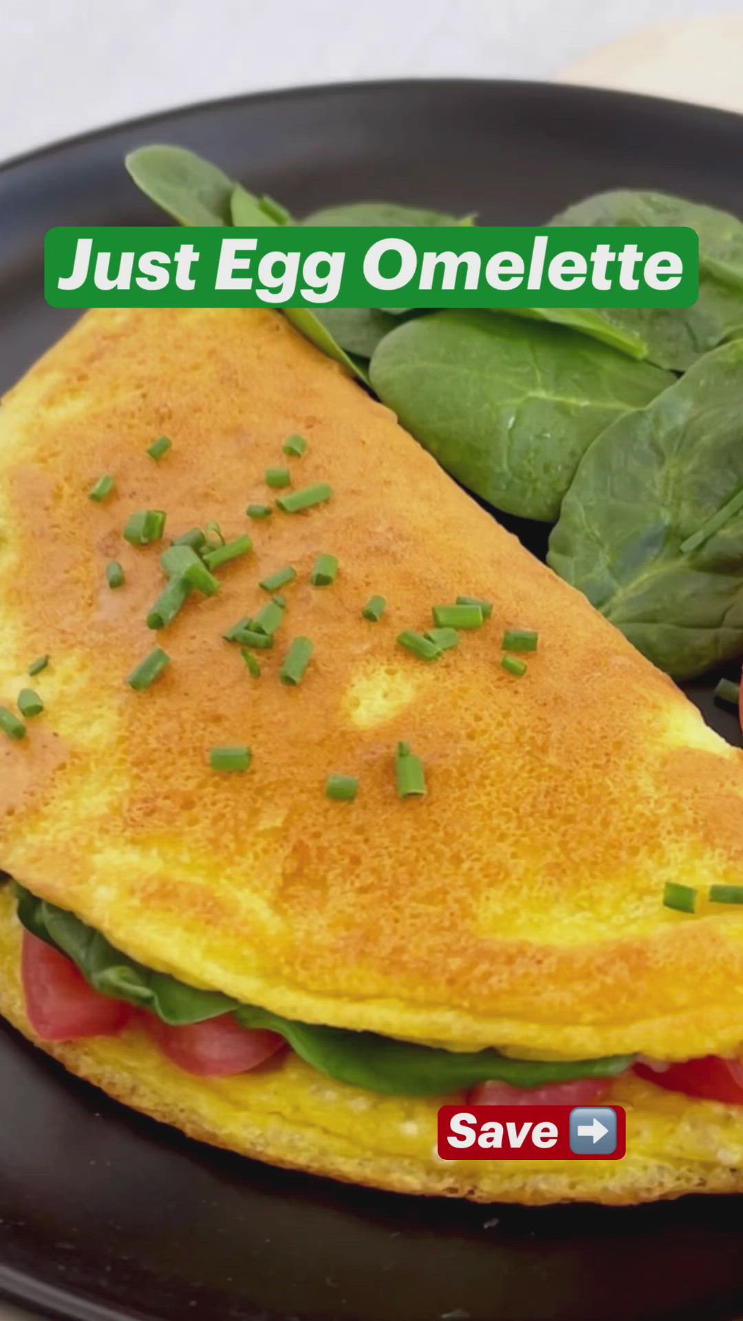 This may contain: an egg omelette on a black plate with spinach leaves and tomato slices