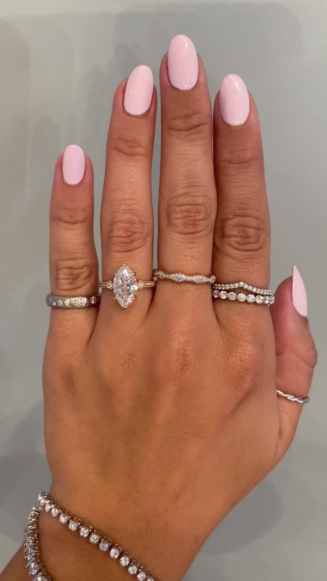 This may contain: a woman's hand with pink manicured nails and three different rings on it