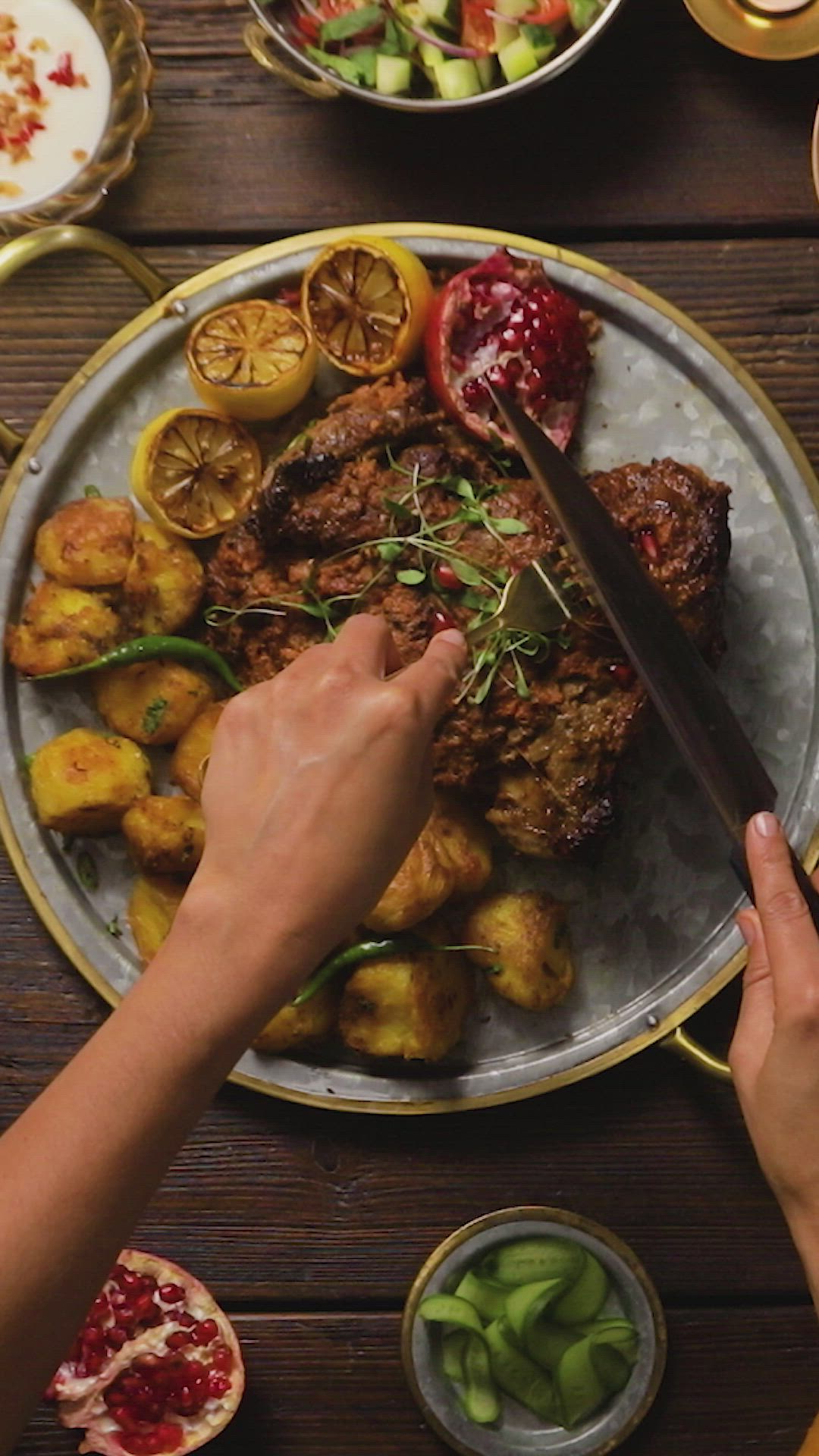 This may contain: a person cutting meat with a knife and fork on a plate next to other food