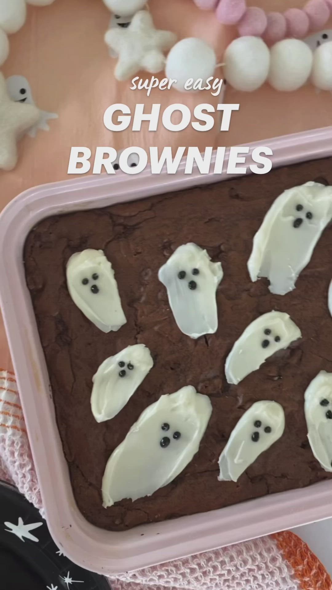 This may contain: chocolate cake with white frosting and ghost faces on it in a pink baking pan