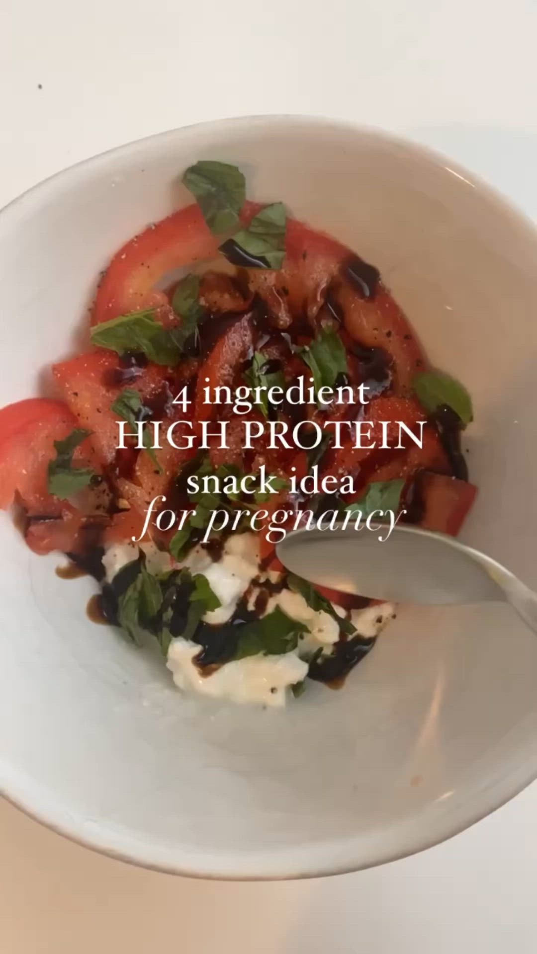 This may contain: a white bowl filled with fruit and vegetables on top of a table next to a spoon