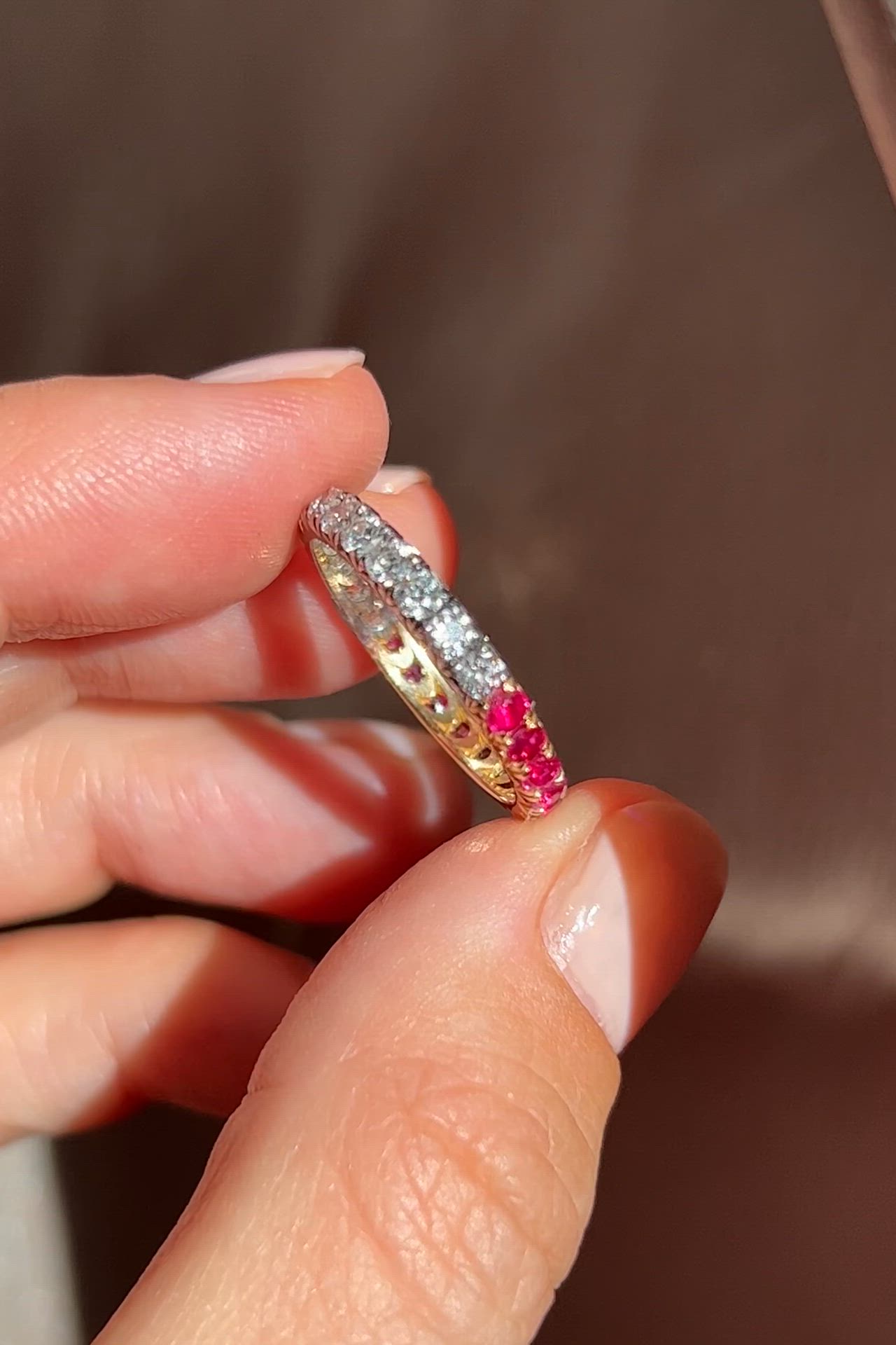 This may contain: a woman holding a ring with pink and white stones