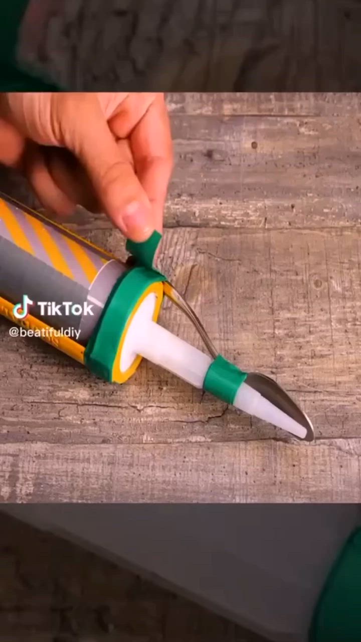 This may contain: a person holding a green and white pen on top of a wooden table