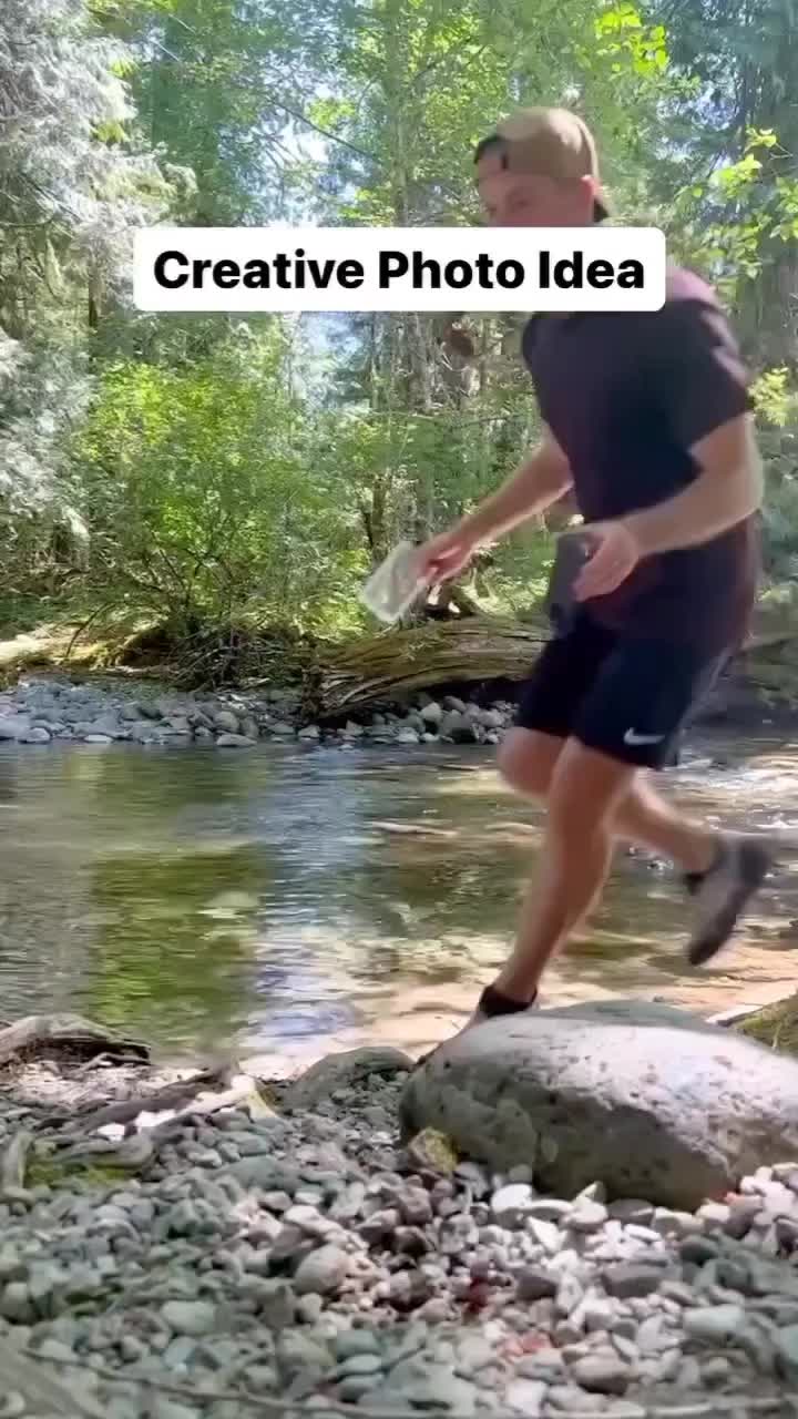 This may contain: a man is playing frisbee on the rocks in the river while another man watches