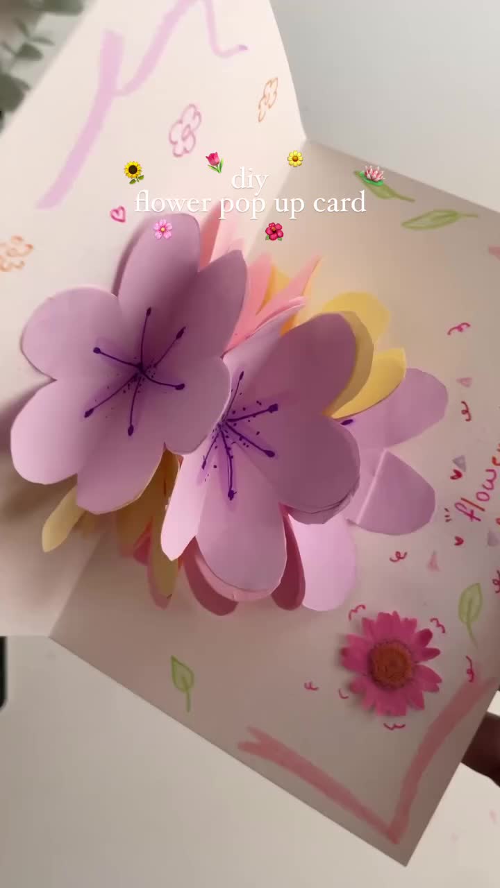 This may contain: a hand holding a flower pop up card