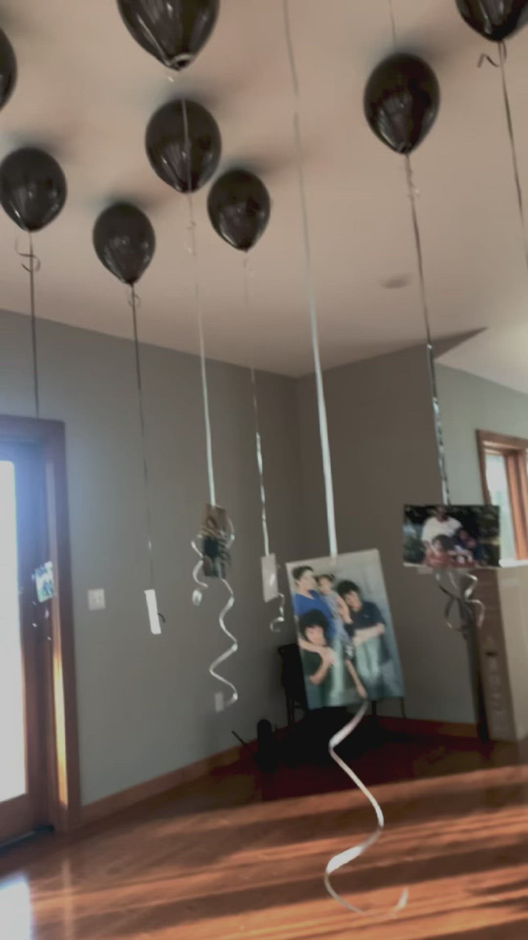 This may contain: some balloons are hanging from the ceiling in a room with wood flooring and gray walls