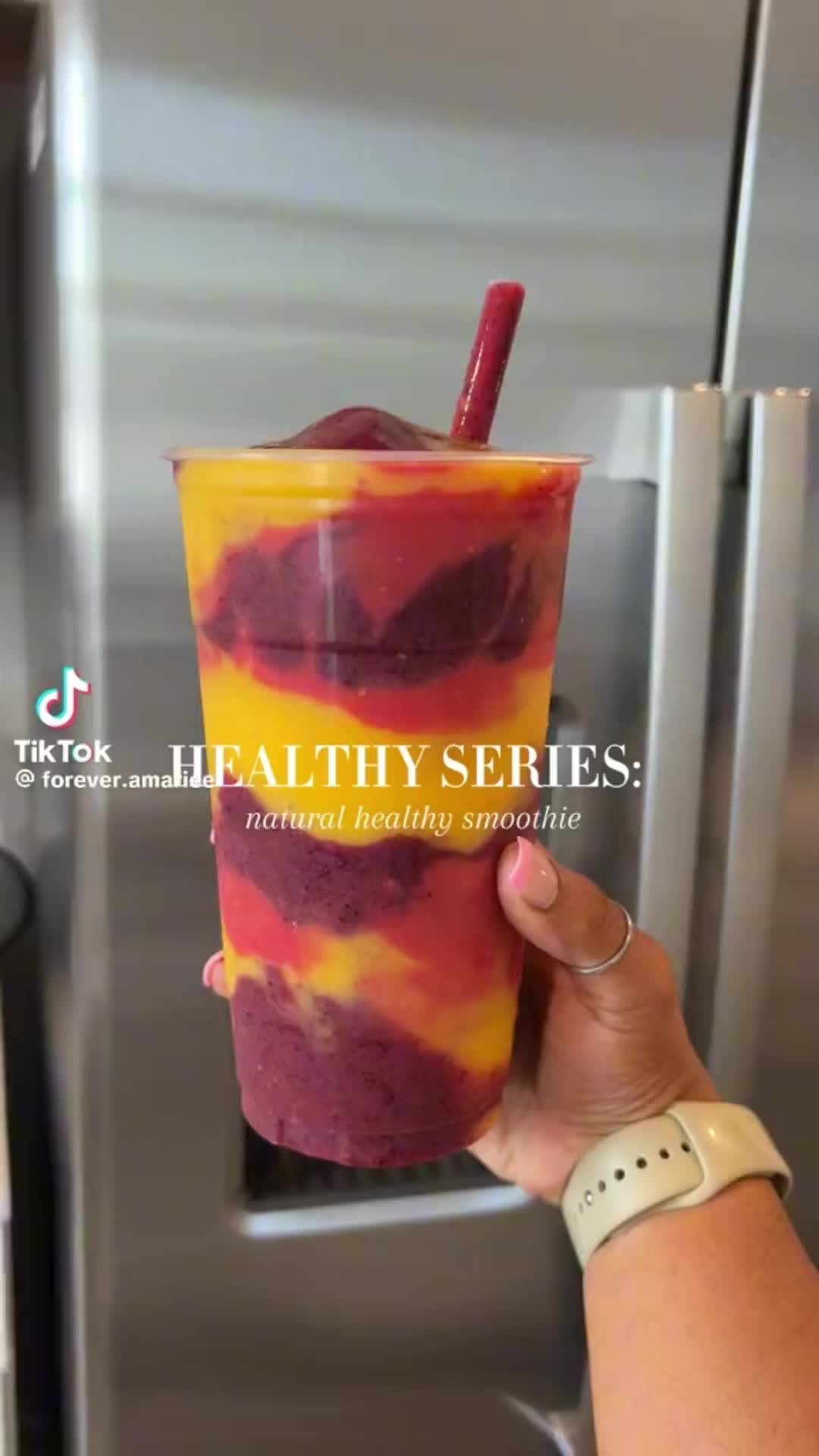 This may contain: a person holding up a drink in front of a stainless steel refrigerator with the words healthy series written on it