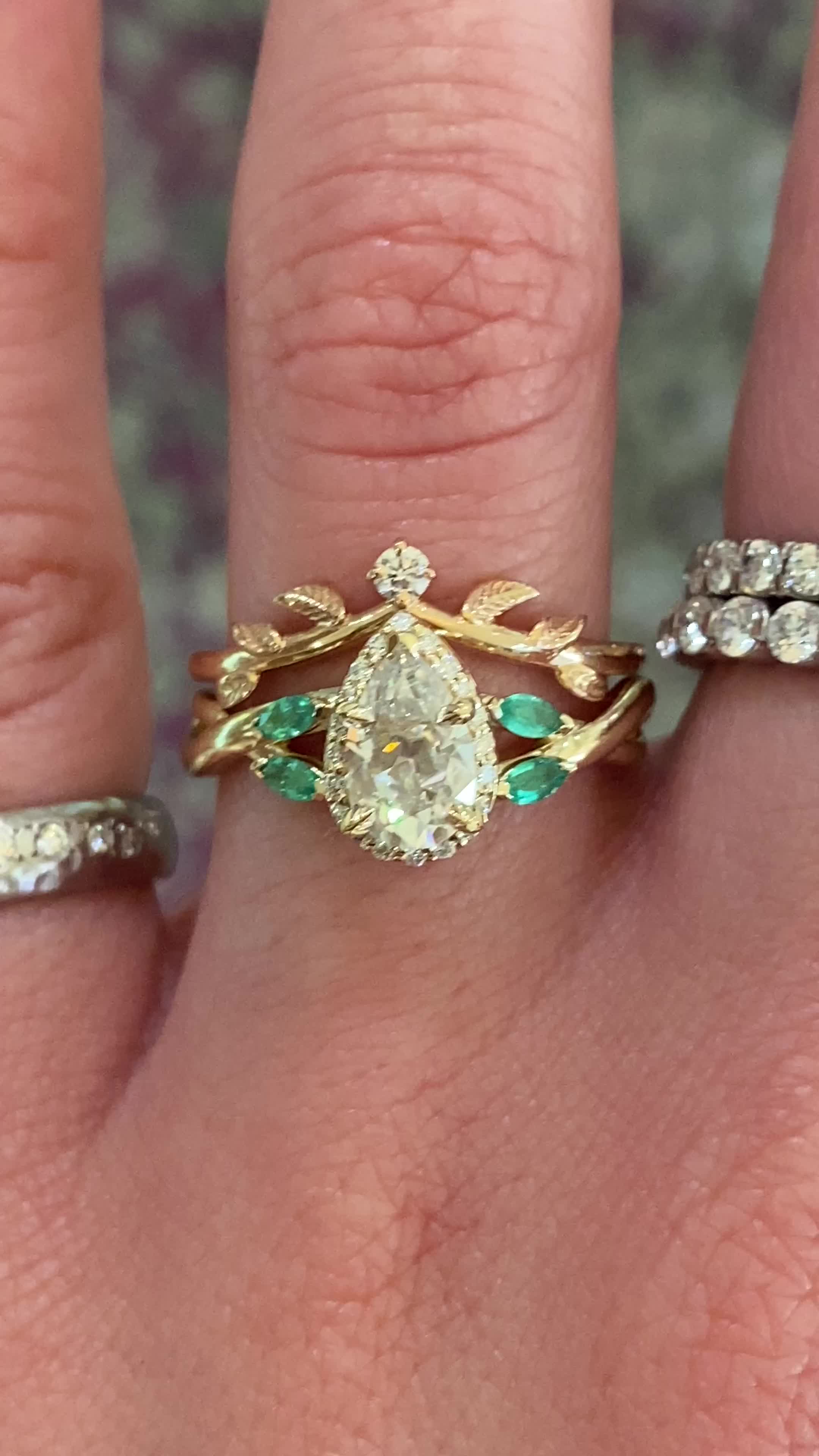 Clover has a natural elegance to her. Her diamond halo gives off a vintage-inspired feel, while the marquise cut green emerald accents and asymmetrical woven band add an organic element. She has a pear brilliant cut at her center hugged by leaf engraved prongs that we know will make your partner's heart melt. Approx Band Width (mm): 1.70mm - 4.00mm Setting Gemstone Quality (side stones): Diamond: Colorless and VS clarity; Emerald: Eyeclean Approx Setting Total Carat Weight (side stones): 0.21 tc