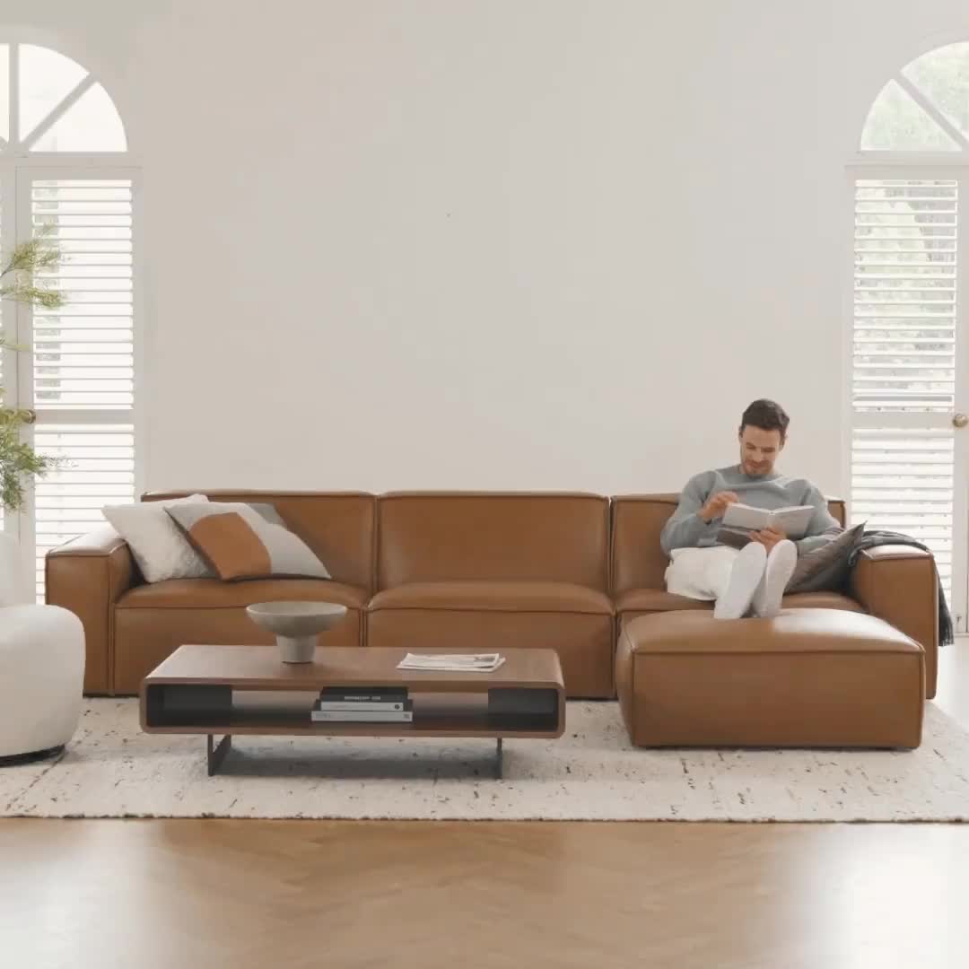 This may contain: a man sitting on top of a brown couch in a living room next to a table