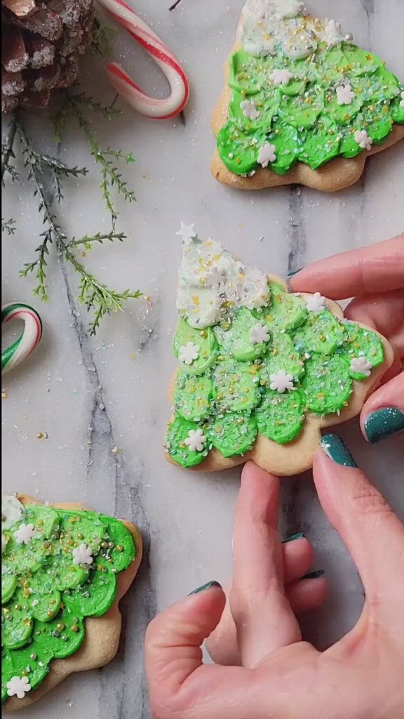 This may contain: someone is decorating christmas cookies with green icing