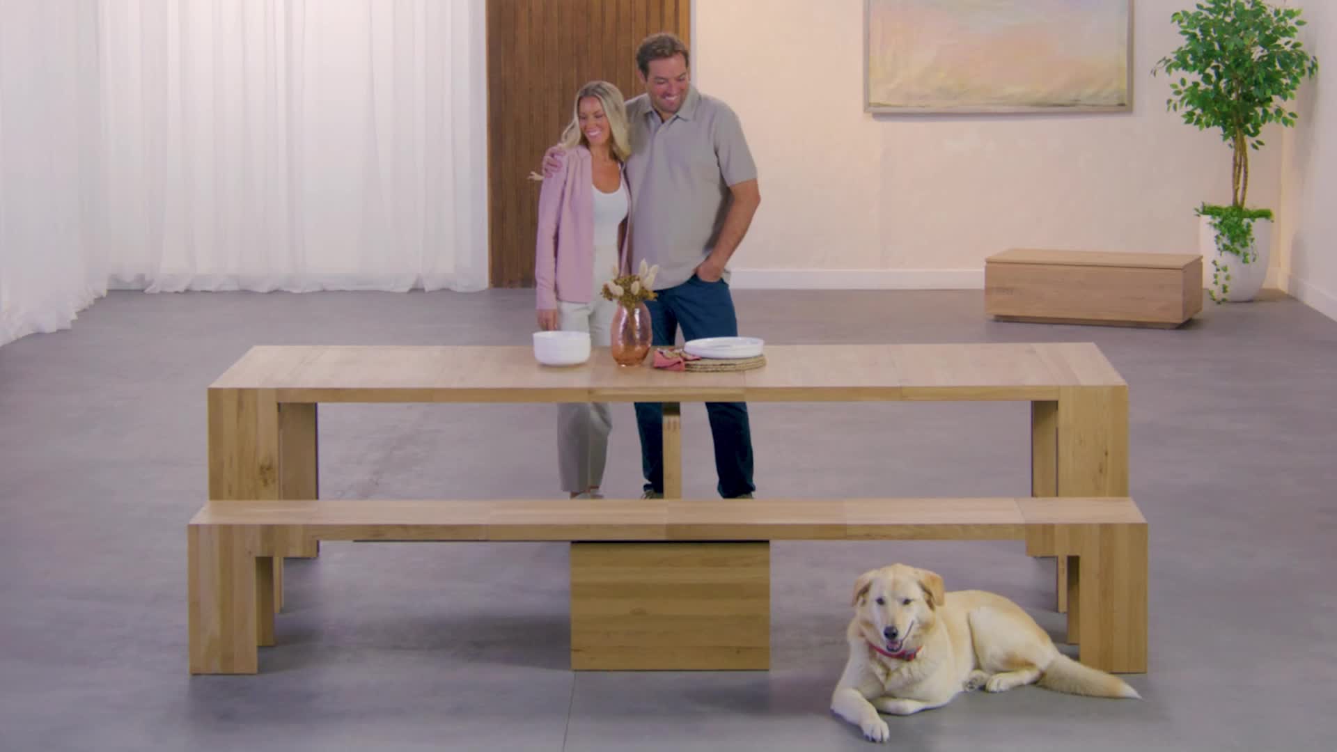 This may contain: a man and woman standing next to a table with a dog laying on the floor