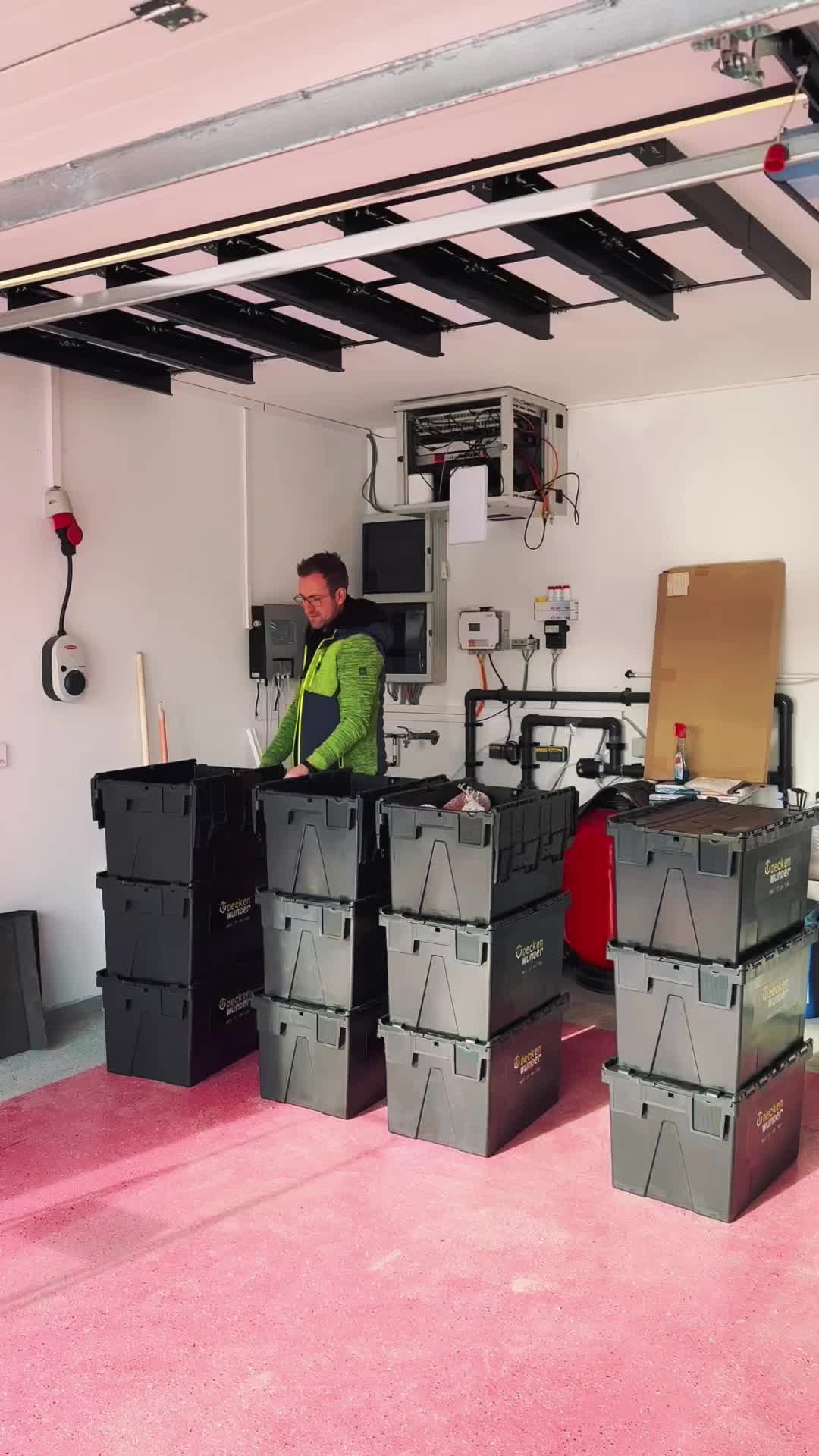 This may contain: a man standing in front of some black boxes on a pink carpeted room floor