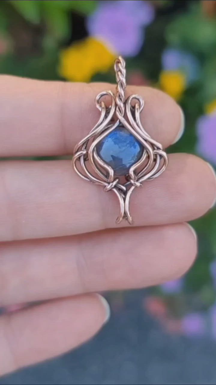 This may contain: a person is holding up a ring with a blue stone in it's center