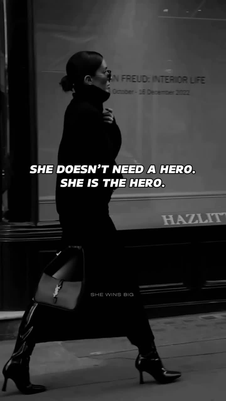 This may contain: a woman is walking down the street with her handbag in her other hand and she doesn't need a hero she is the hero