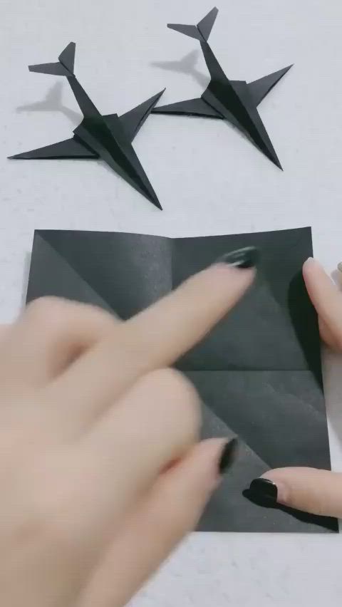 This may contain: two hands are holding black origami birds