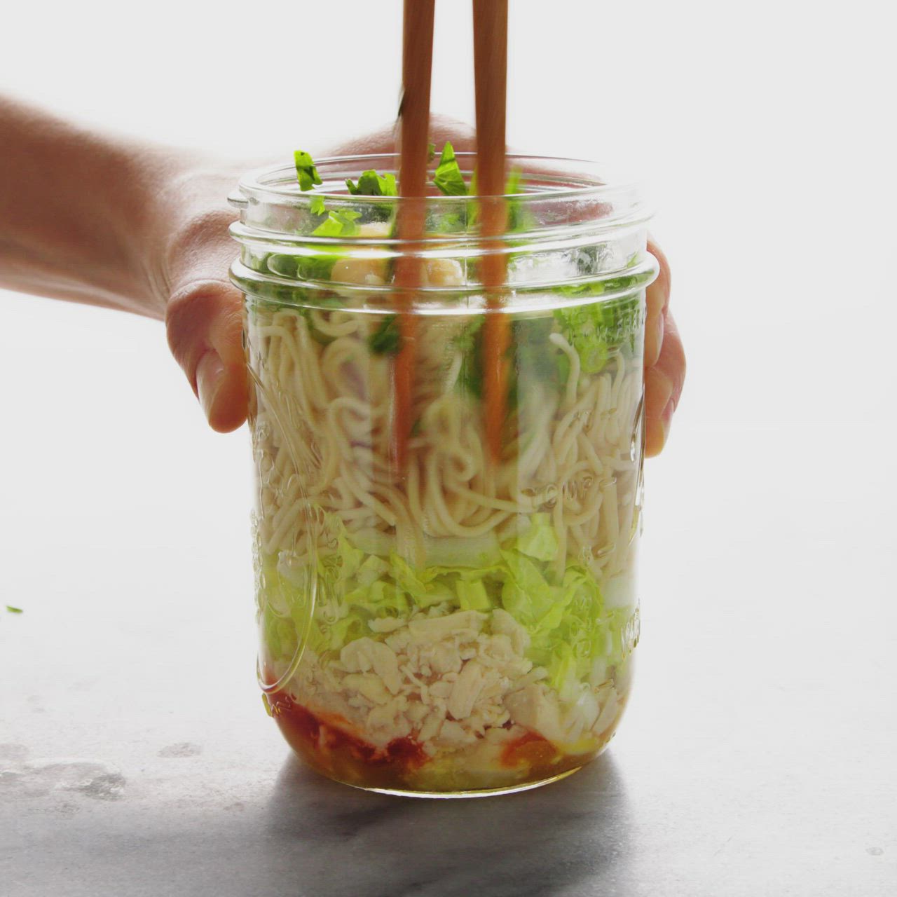 This may contain: someone is holding chopsticks over some noodles in a jar with the words how to make homemade cup noodles